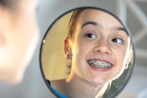 Caucasian preteen girl with braces on her teeth looking at the mirror