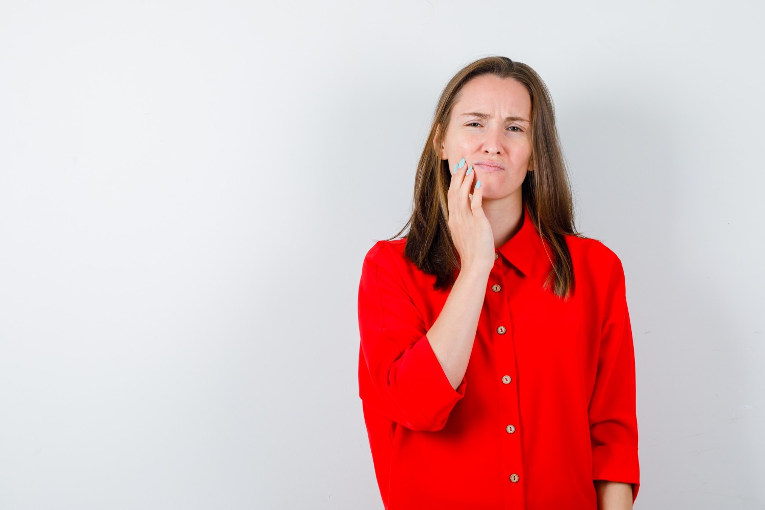 Young woman in red blouse suffering from toothache and looking painful