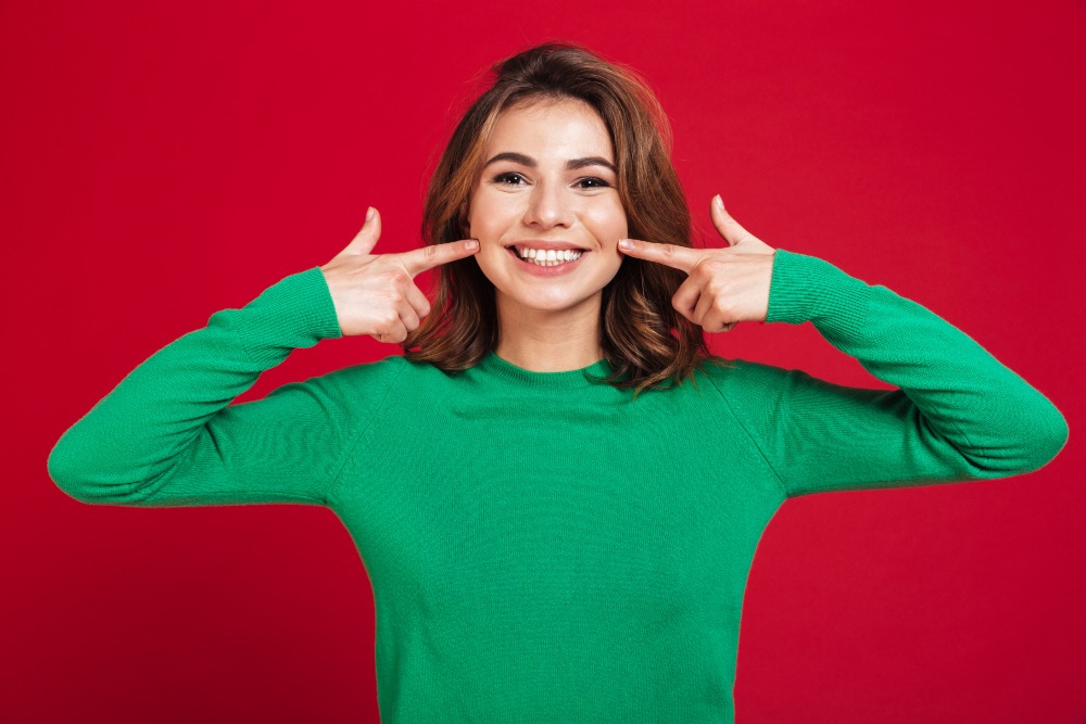 Excited happy young pretty woman, pointing towards smile after taking smile makeover treatment